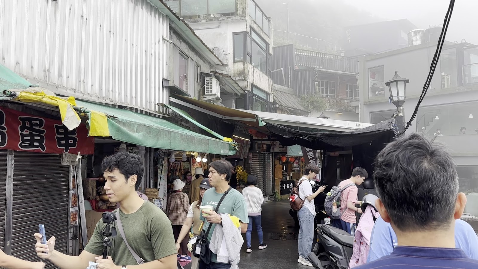 霧雨朦朧的九份老街，遊客漫步商店間