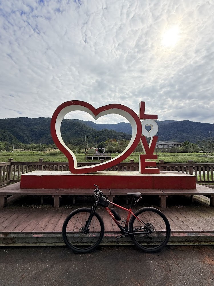 大型LOVE裝置前方停著自行車，背景有山脈