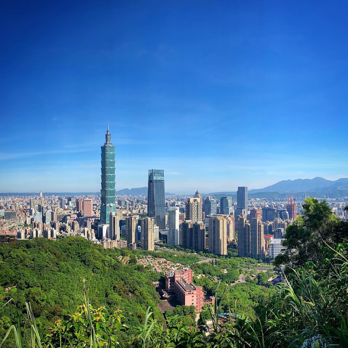 象山步道俯瞰信義區一日遊景點全景，台北101高聳入雲藍天
