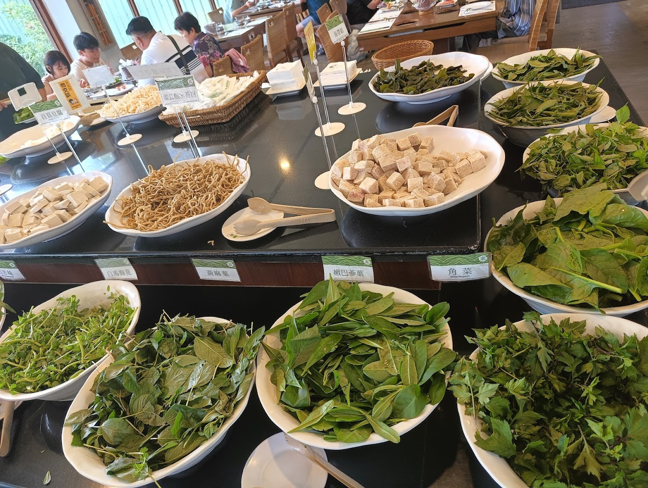 自助餐檯上擺放各種新鮮蔬菜豆腐麵條與根莖類食材
