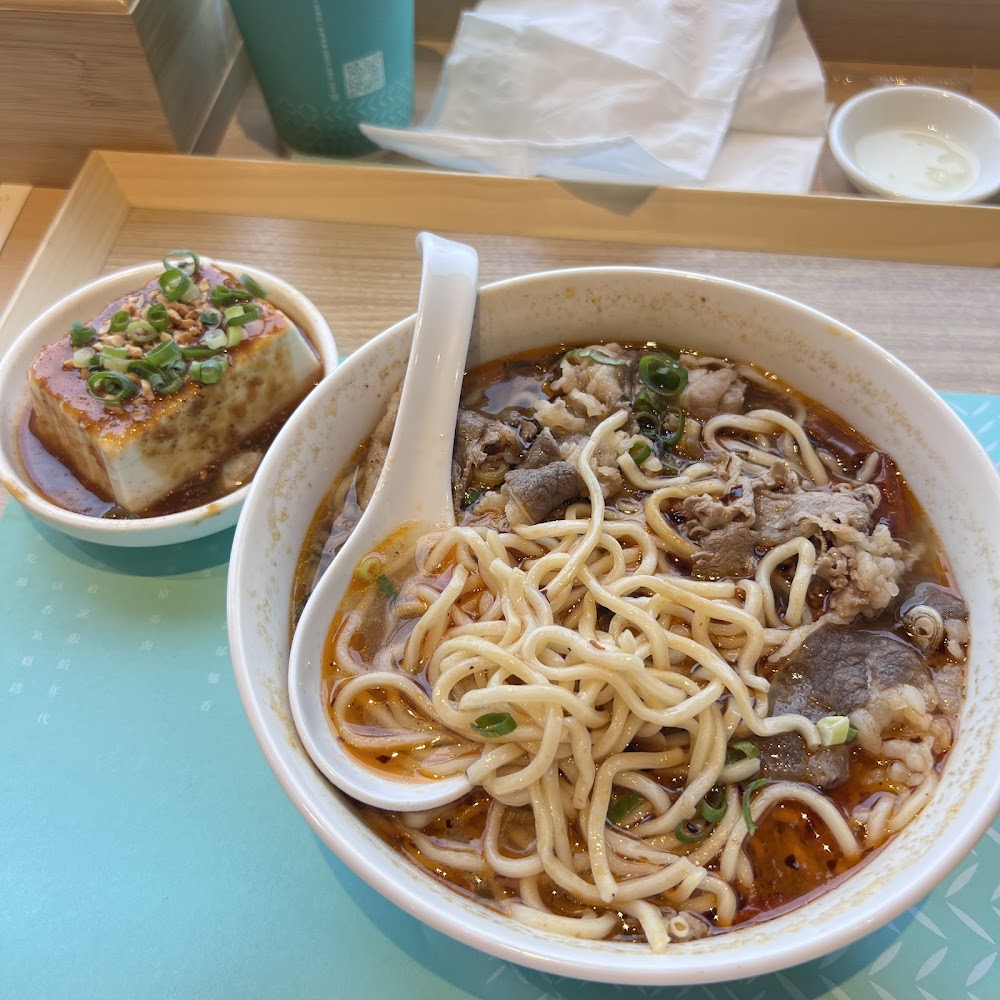 牛肉麵與嫩豆腐小菜，紅亮湯頭搭配牛肉片。