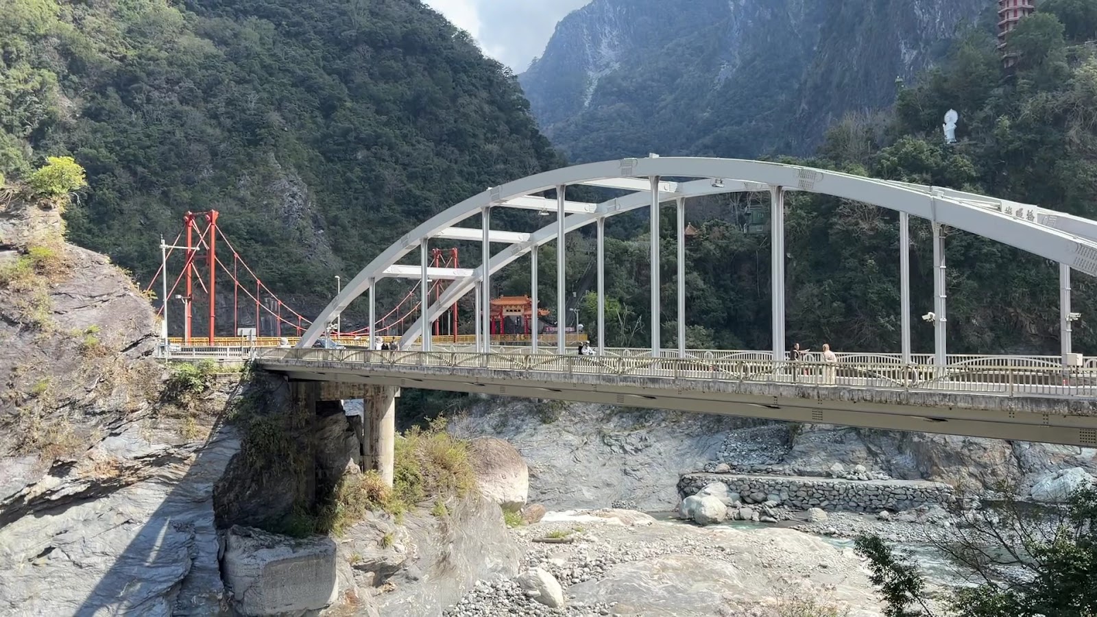 太魯閣國家公園入口白色拱橋，橫跨立霧溪，背景峽谷峭壁與廟宇