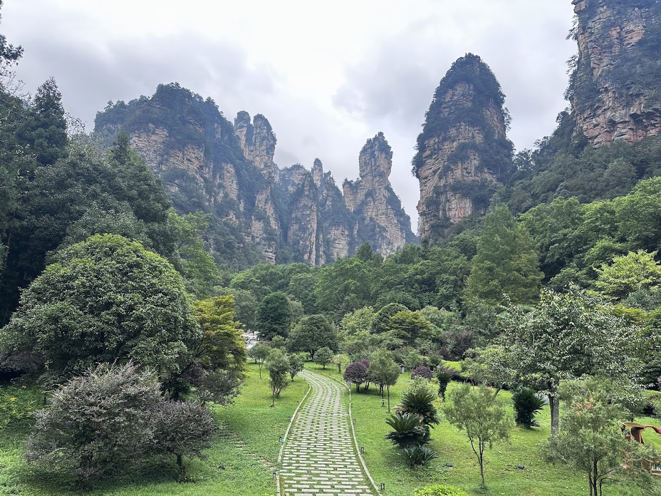 石板步道穿越森林,遠方有高聳奇岩山景