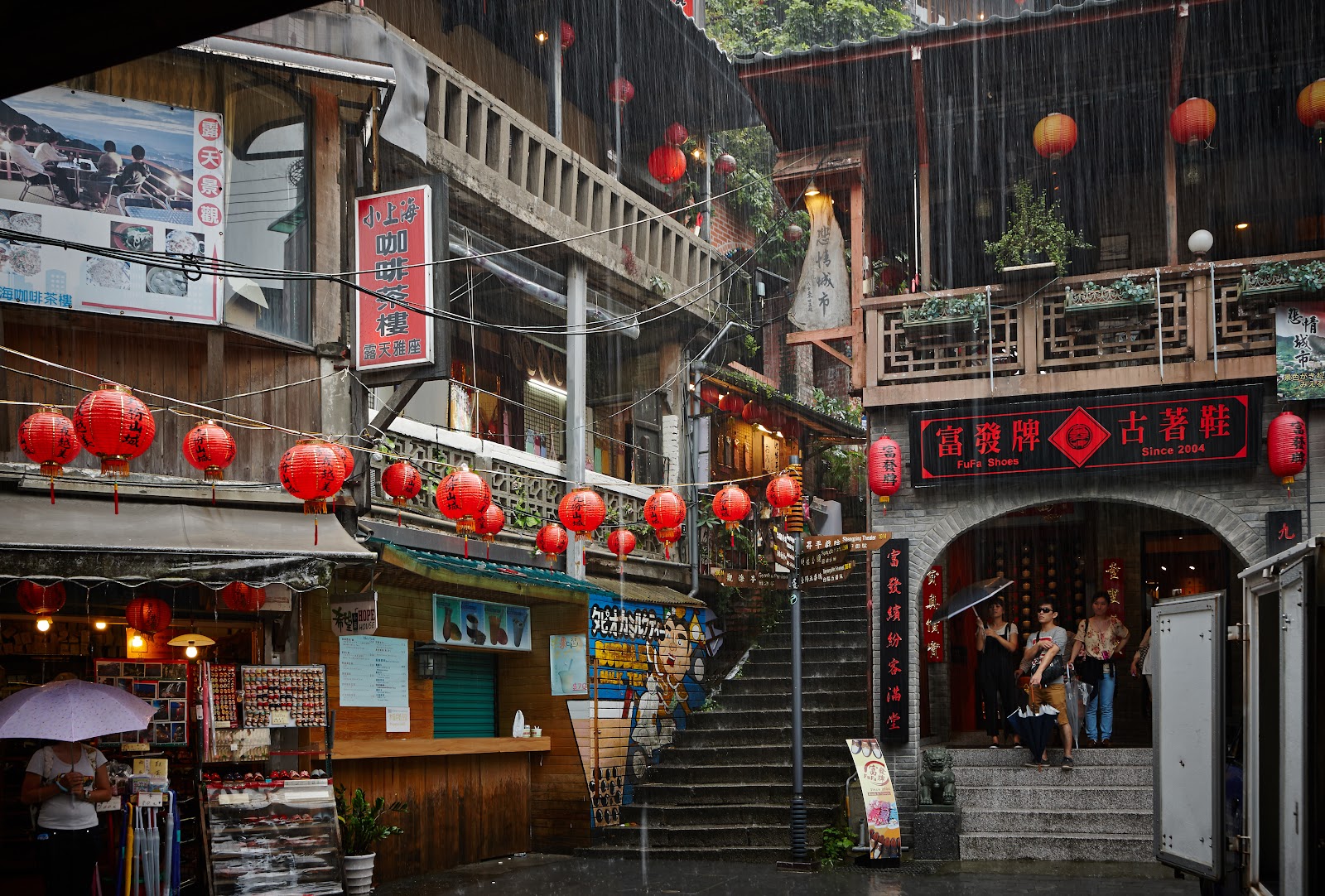 雨天九份老街，紅燈籠映照在濕潤石板路上