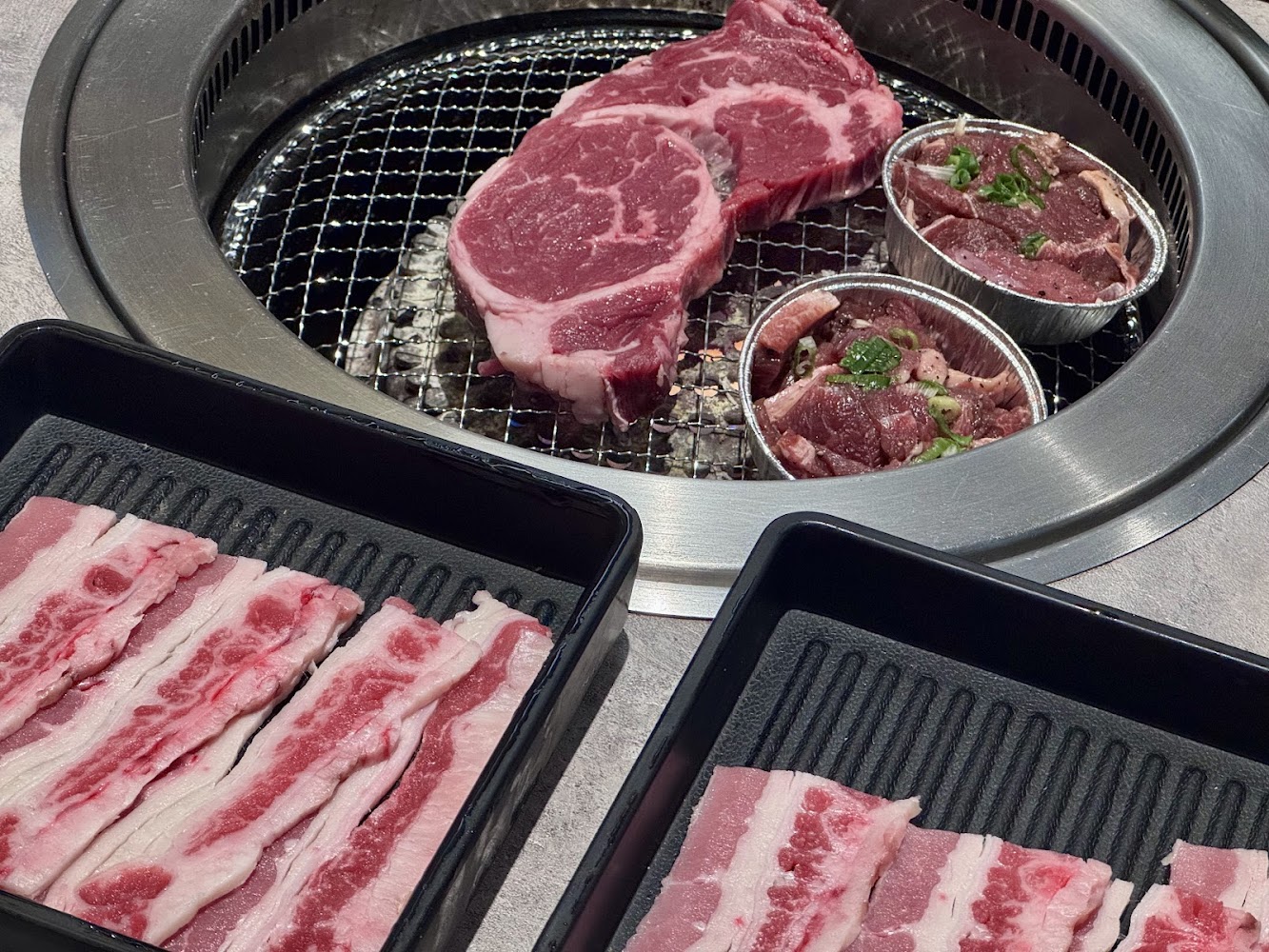 燒烤桌上有生牛排、調味牛肉片與切片五花肉