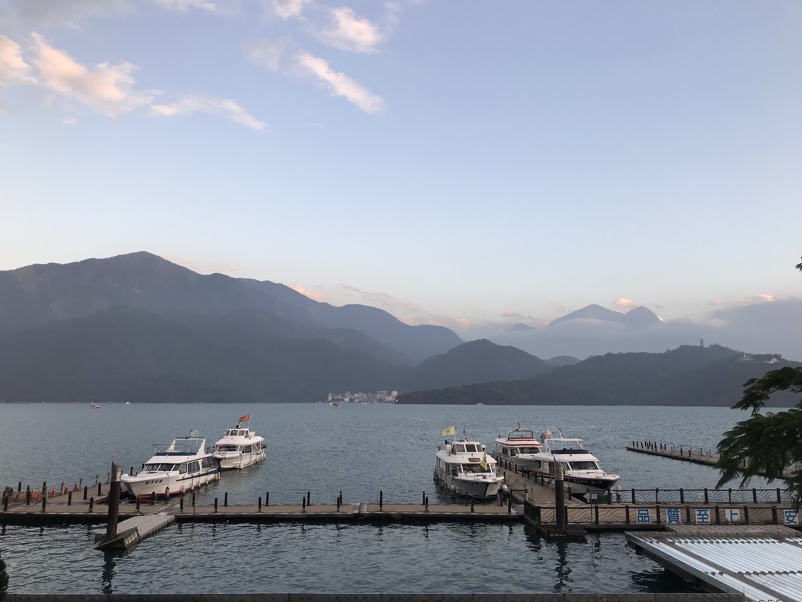 水社碼頭黃昏，遊艇停靠棧橋，背景為日月潭群山