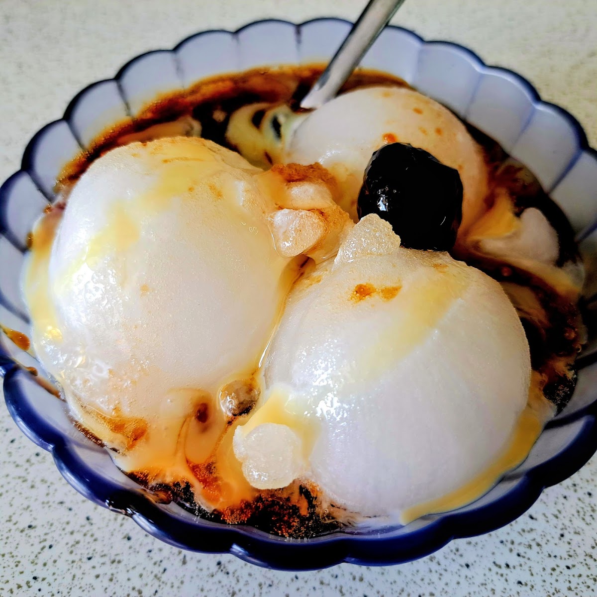 建華冰店仙草牛奶冰，三顆白色冰球搭配黑色仙草，淋上焦糖醬