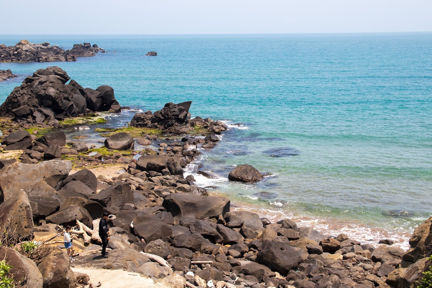 自然岩岸與遊客行走其間的寧靜海邊風景