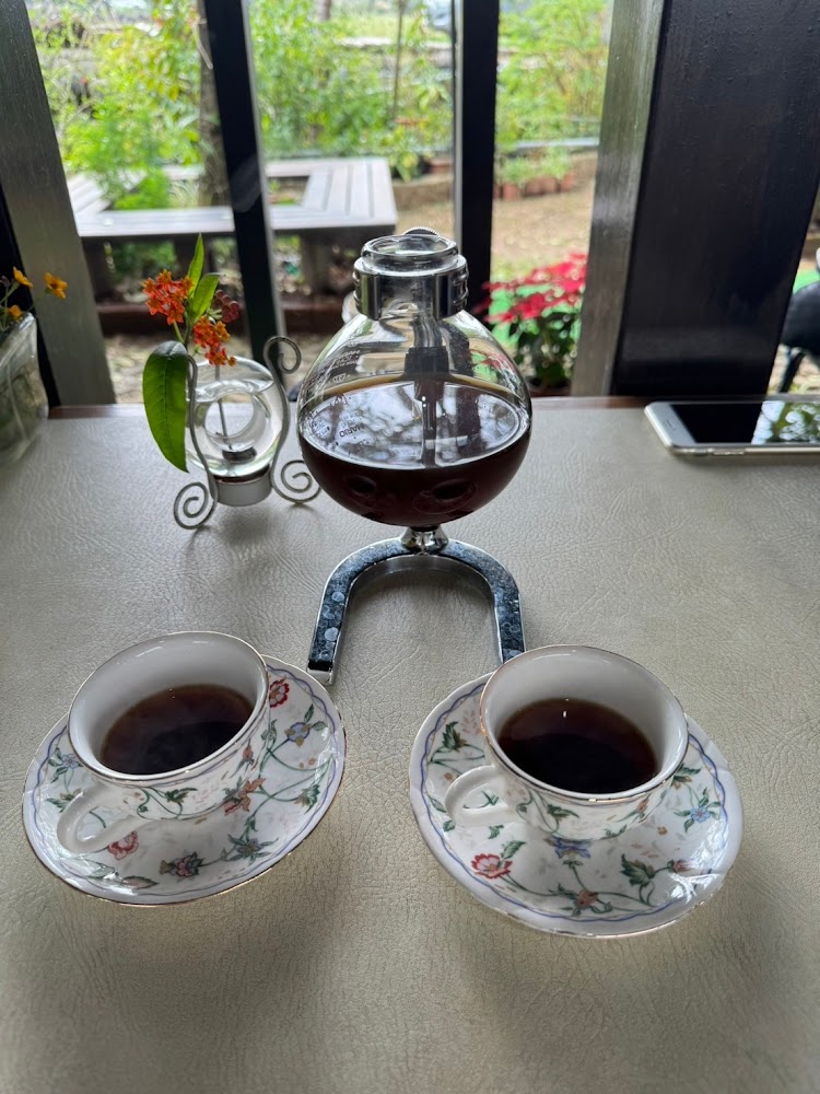 戶外庭園景色旁的花紋瓷杯咖啡組