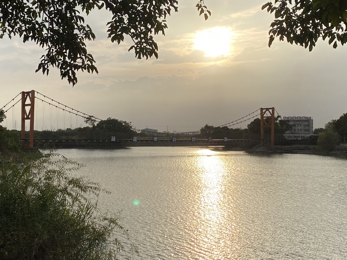 葫蘆埤自然公園夕陽下的橙色吊橋與水面倒影