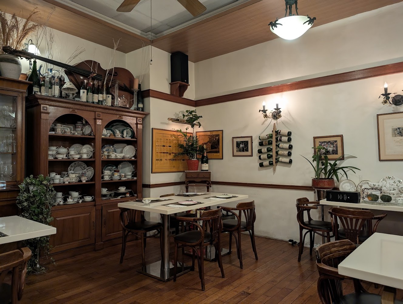 餐廳內有許多木製餐具櫃，展示精緻瓷器與杯盤，牆上掛有照片與酒瓶裝飾
