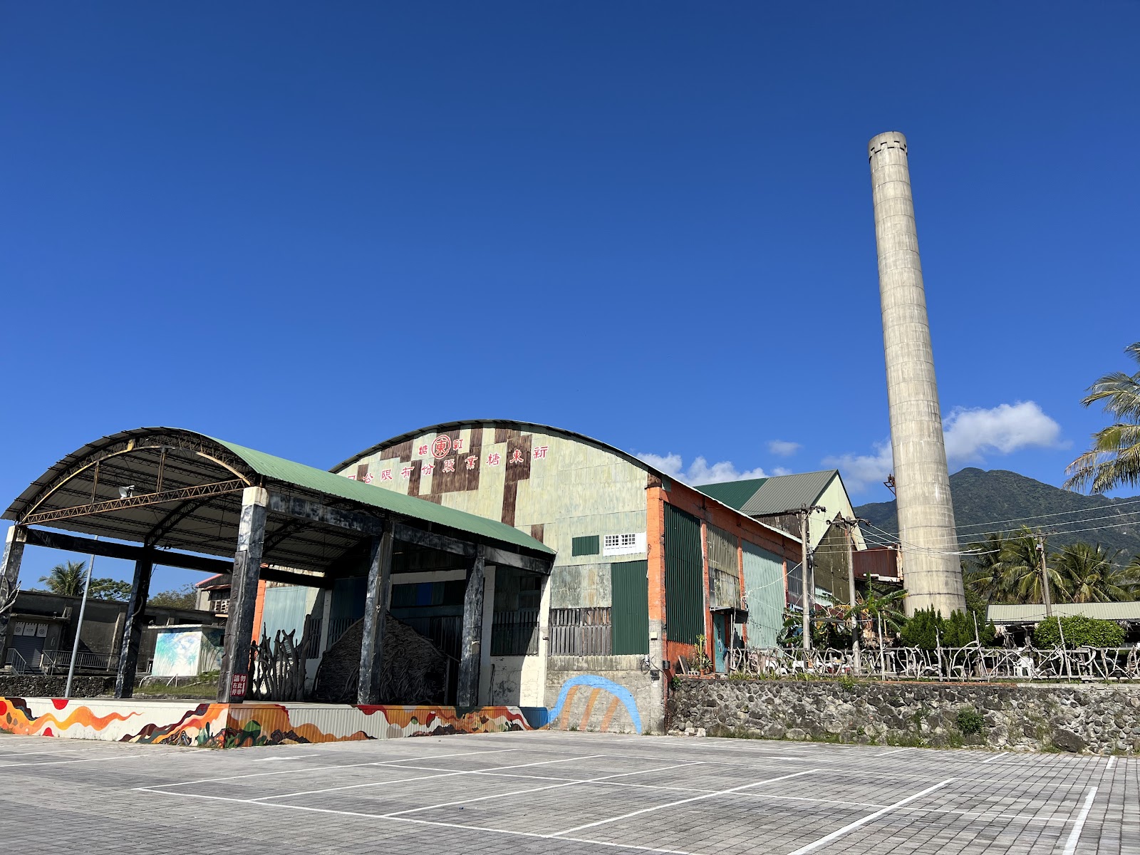 都蘭新東糖廠舊廠房外觀，高聳煙囪與彩繪外牆融合工業遺產與原住民藝術