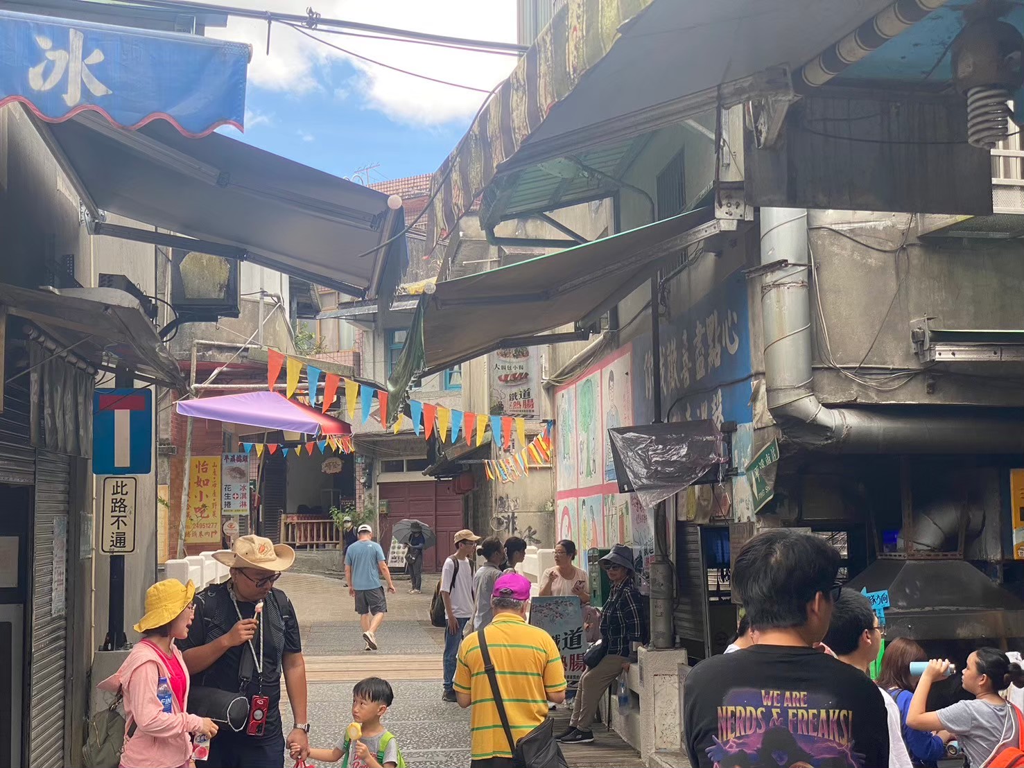 平溪老街小巷，冰字旗幟，彩色三角旗，遊客漫步