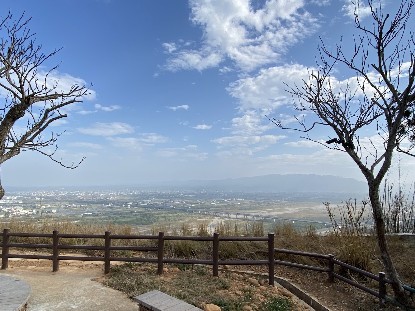 觀景台前方有木欄杆座椅遠方可見平原山脈與藍天白雲