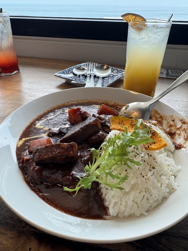 牛肉咖哩飯搭配飲料，背景是靠海窗景