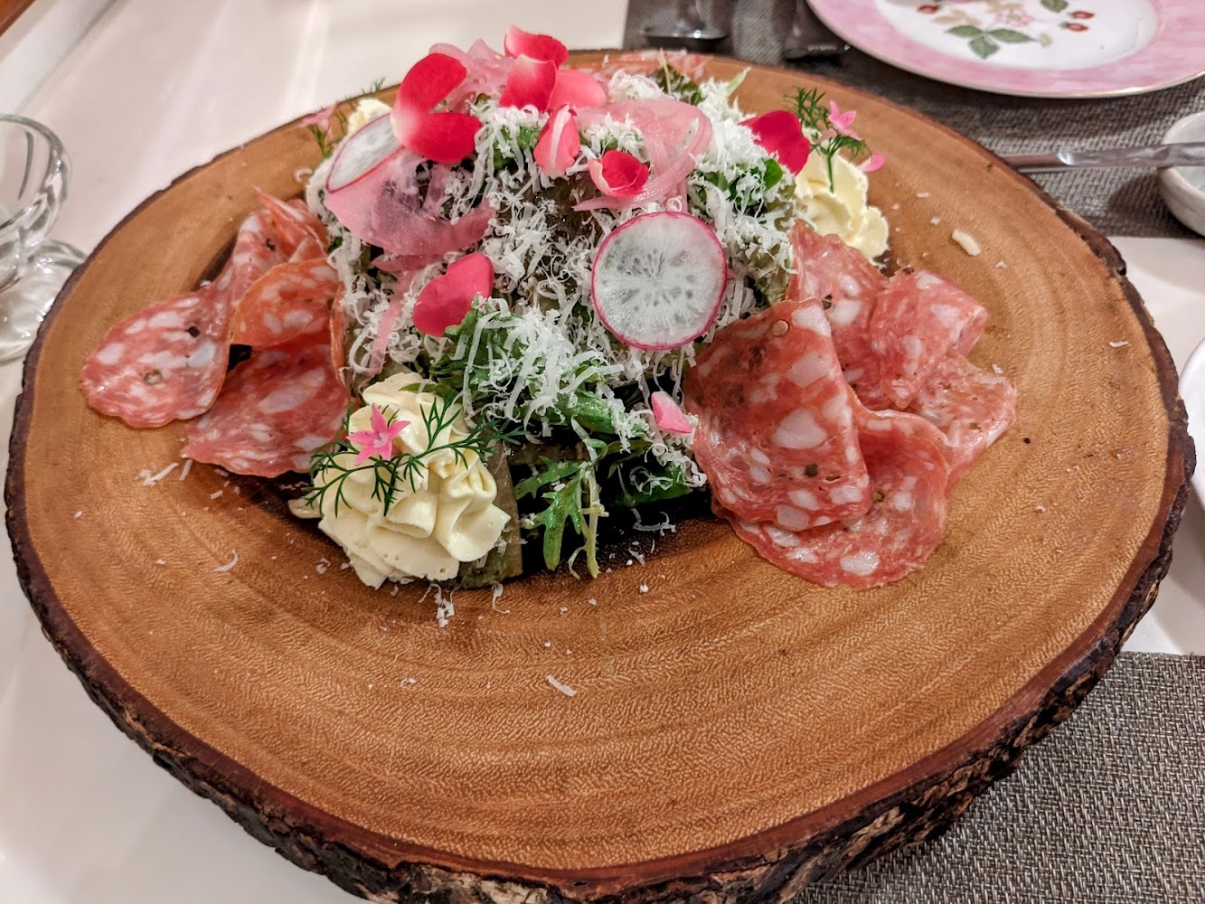 精緻沙拉，搭配火腿、奶油裝飾與蔬菜，並以花瓣和切片蘿蔔點綴