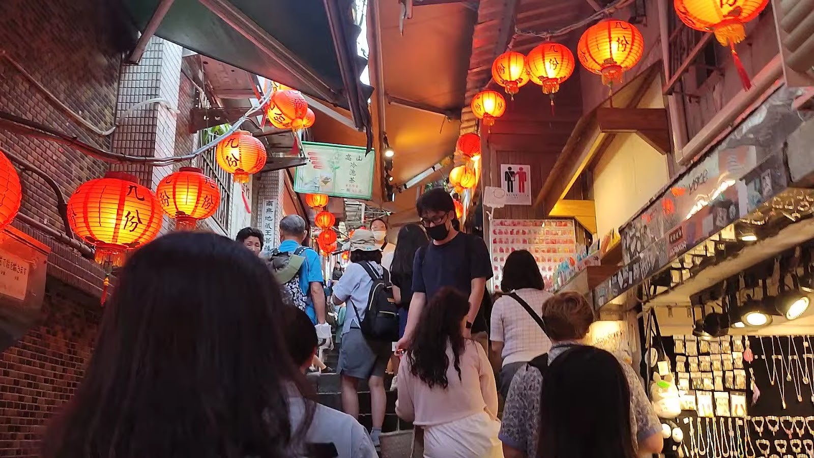 九份老街巷弄間紅燈籠高掛，遊客穿梭其間，充滿懷舊老街氛圍