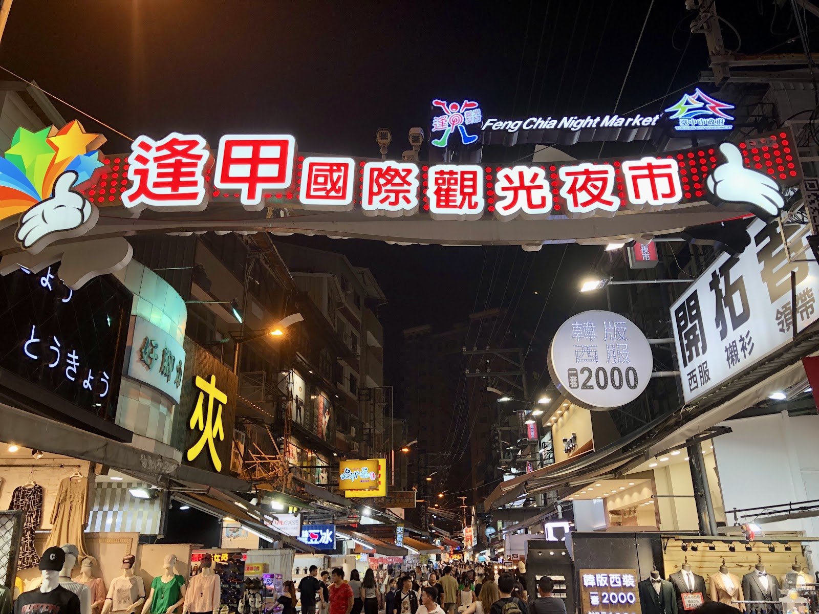 逢甲國際觀光夜市牌樓正面特寫，中英文招牌清晰可見，夜晚燈光璀璨