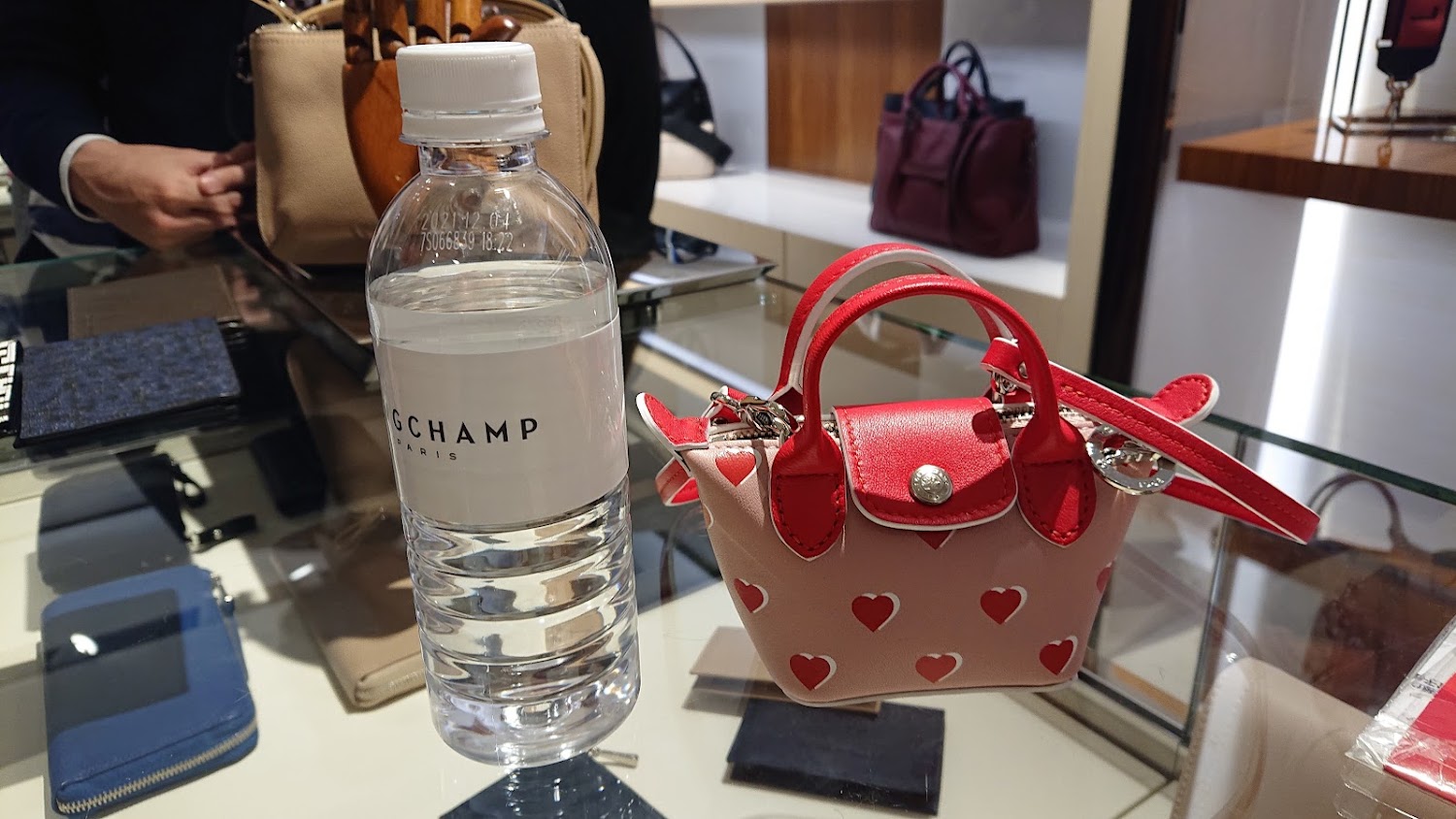 Longchamp 台中三民店桌上展示品牌瓶裝水與迷你紅色愛心包