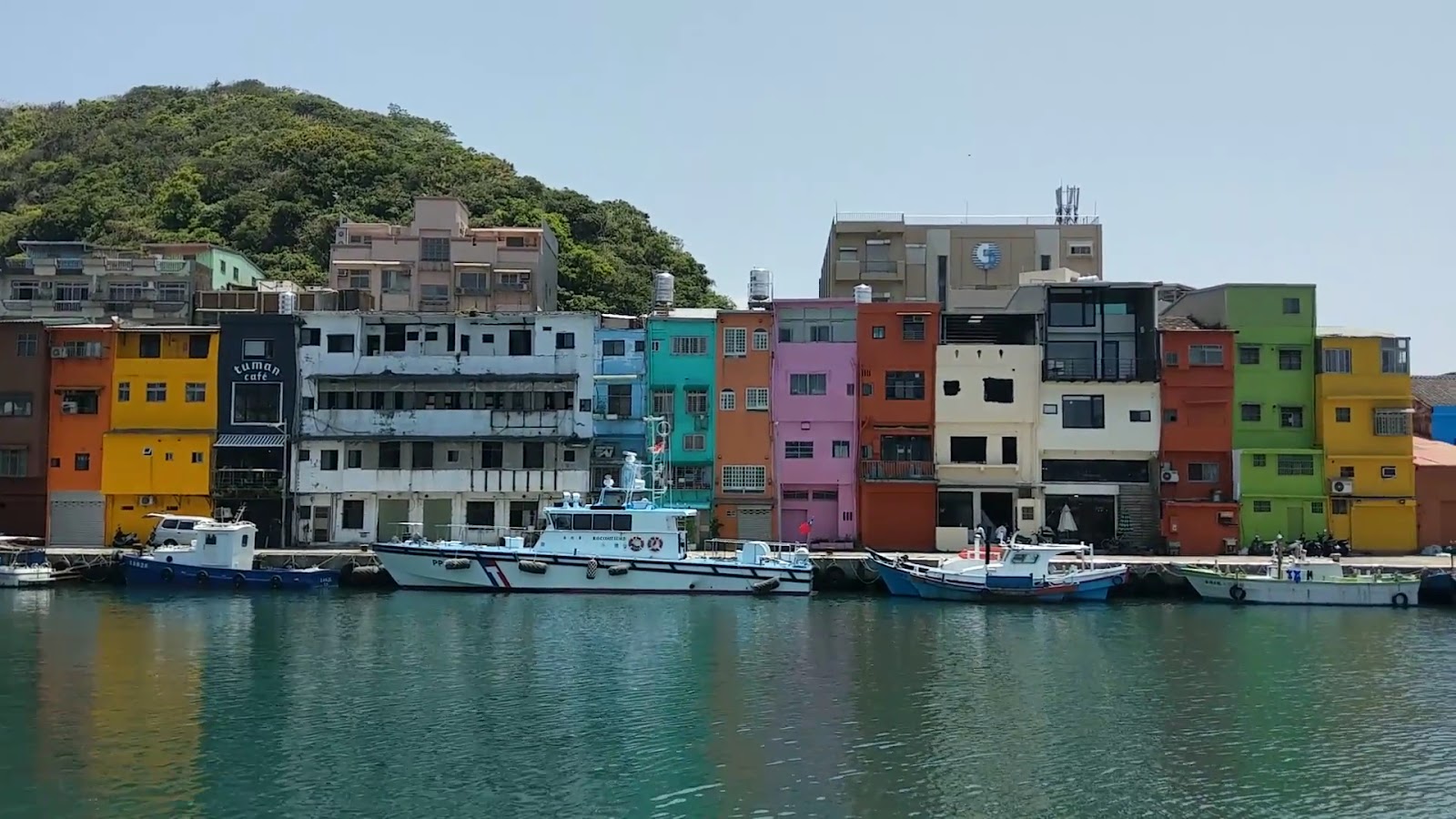 正濱漁港彩色屋全排，各棟色彩鮮明，白色巡邏艇停靠
