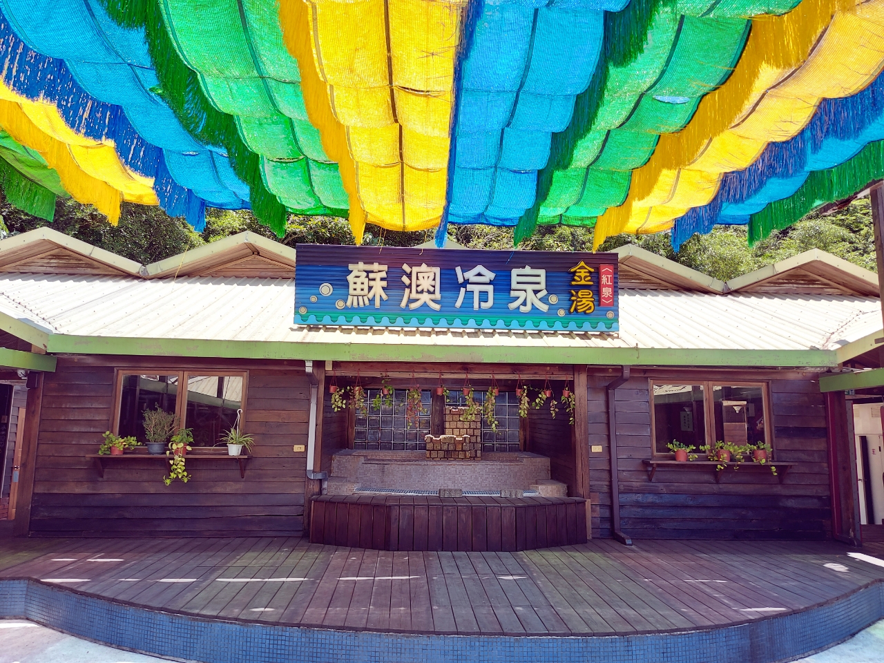 蘇澳冷泉傳統湯屋入口，木造建築，頭頂彩色流蘇裝飾，宜蘭蘇澳老字號