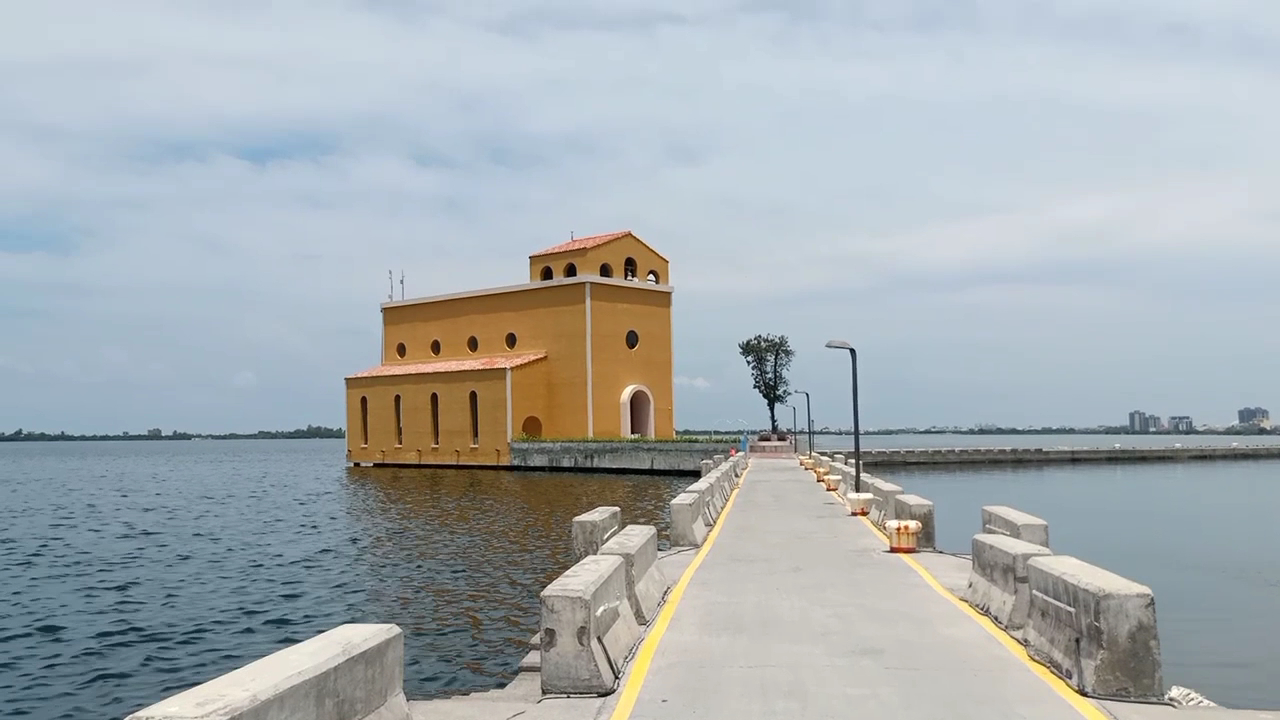 橘黃色建築位於水面上旁邊有長堤道連接岸邊天空晴朗
