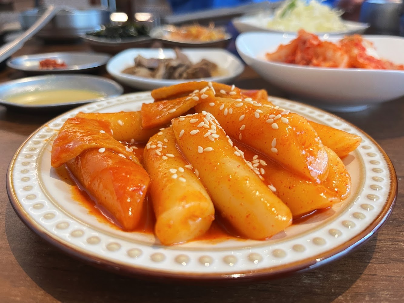韓式辣炒年糕灑上白芝麻，搭配多樣韓式小菜