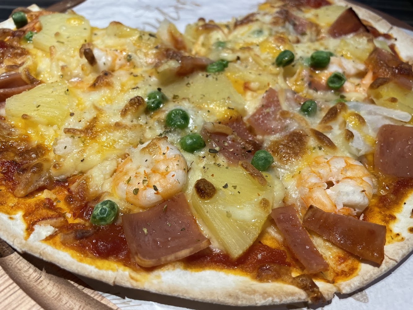 披薩上有蝦仁火腿鳳梨青豆與起司