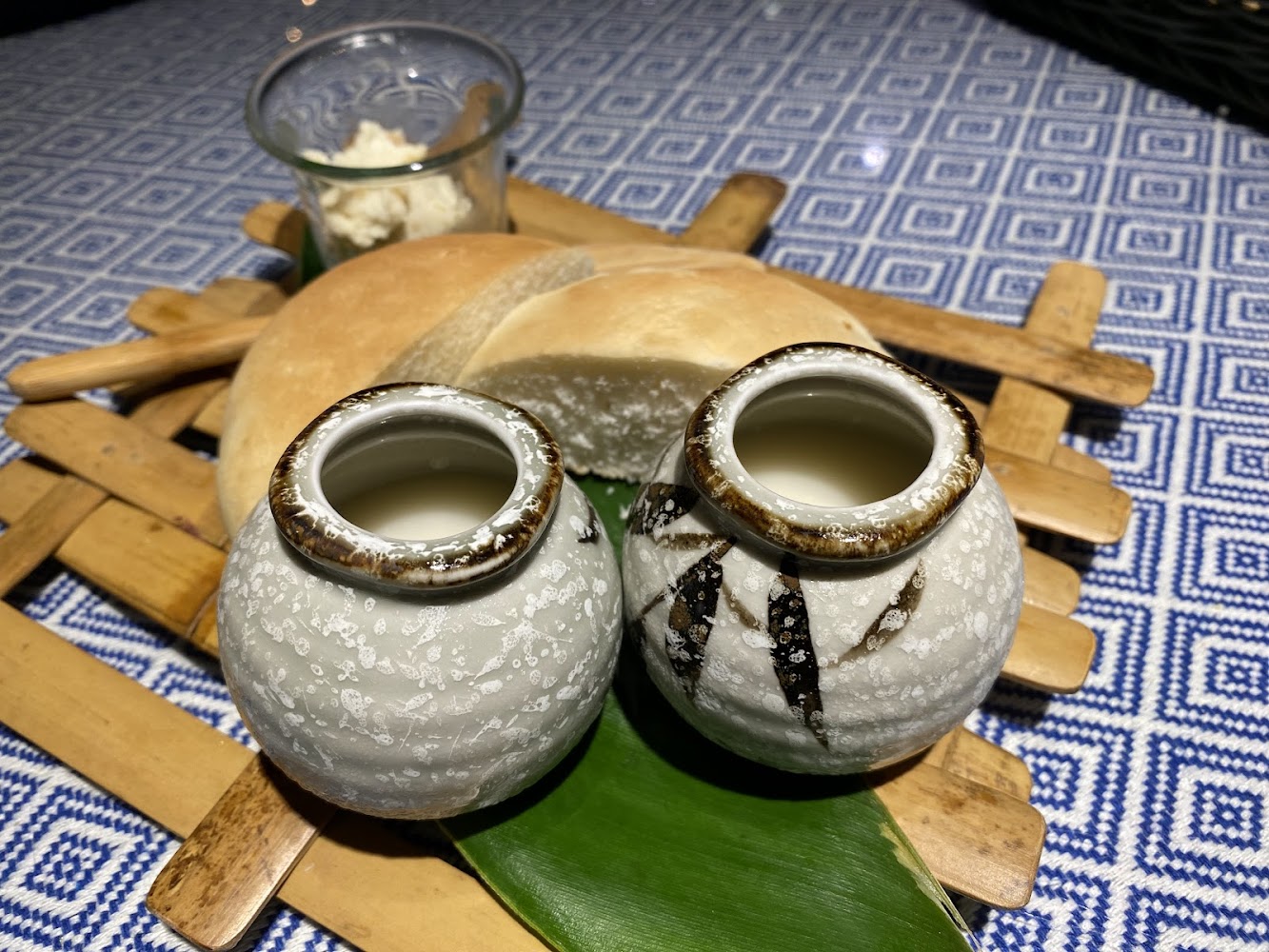 兩個陶瓷酒壺搭配麵包與奶油放在木盤上