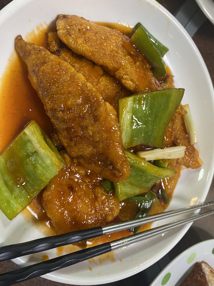 中式料理，盤中有多塊酥炸魚片，搭配青椒和蔥段，外層裹著帶有紅色醬汁