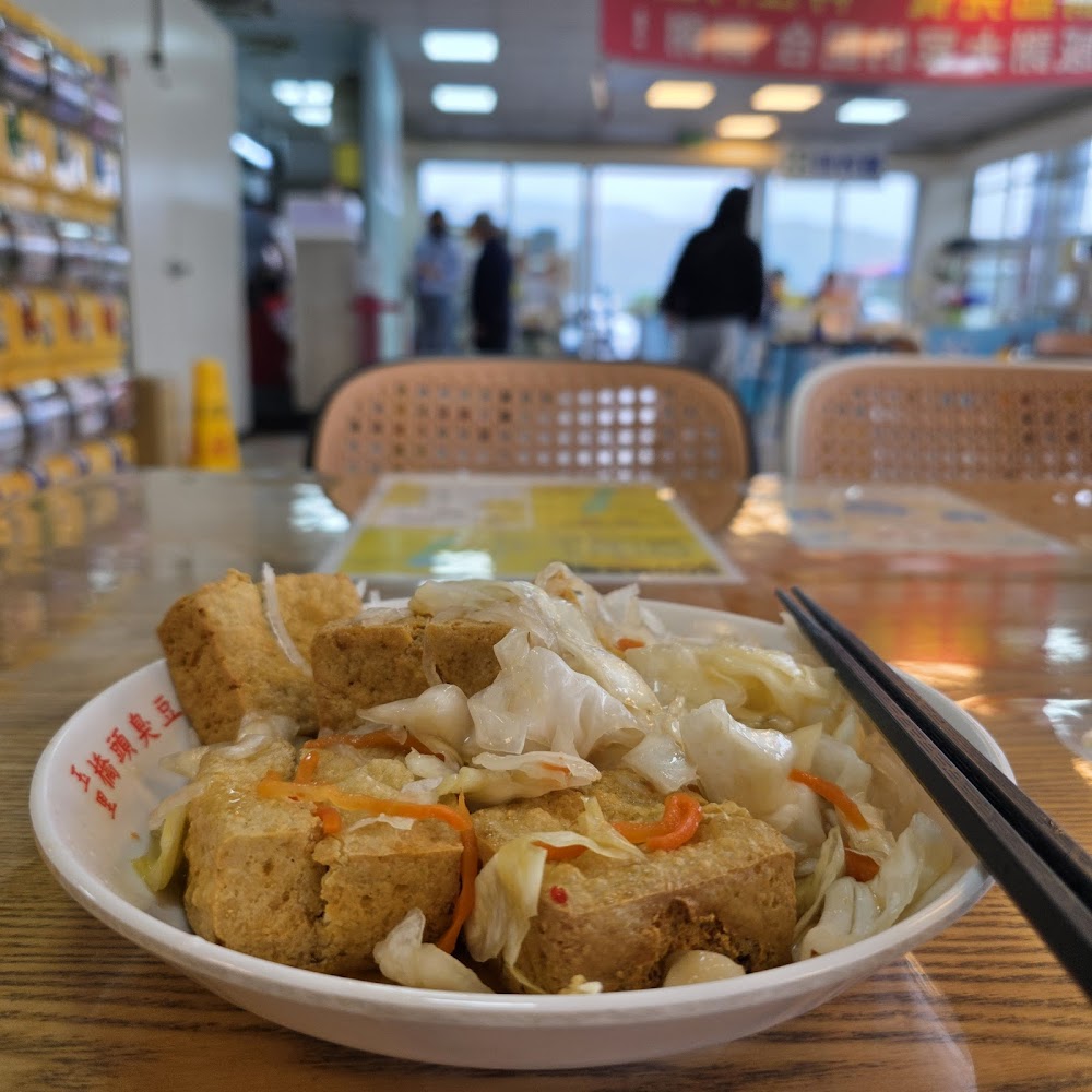 一碗臭豆腐上鋪泡菜，背景為明亮用餐區