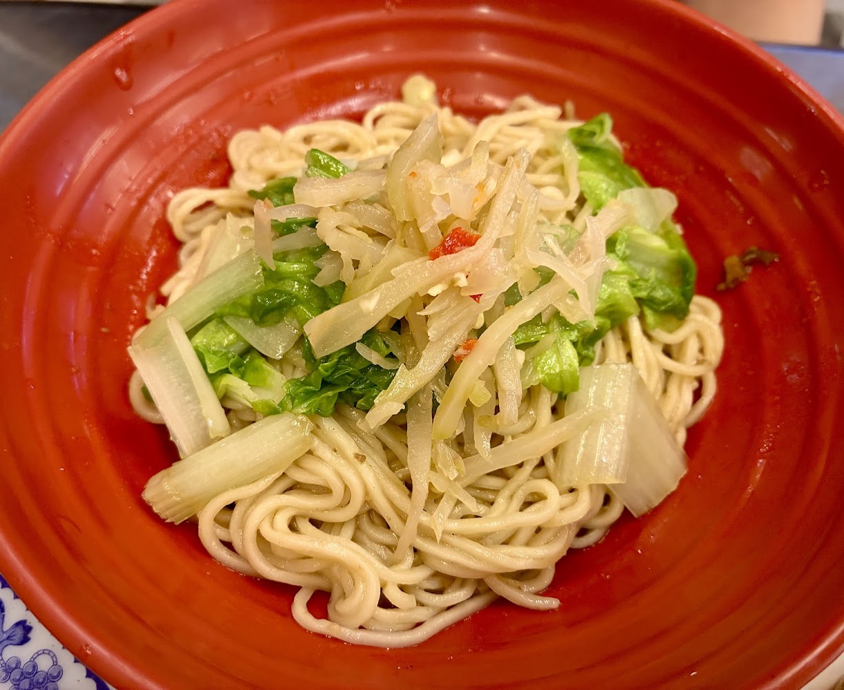 一碗乾拌麵上鋪有青菜與醃製蔬菜絲看起來清爽健康