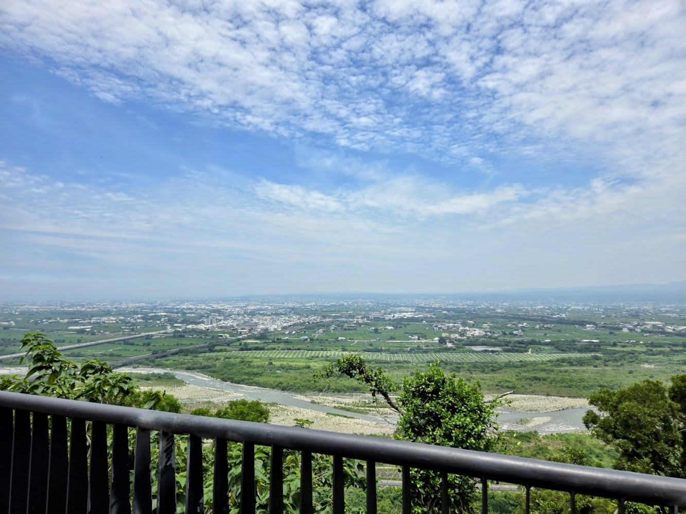 觀景台欄杆遠方可見大片農田河流藍天白雲與城鎮