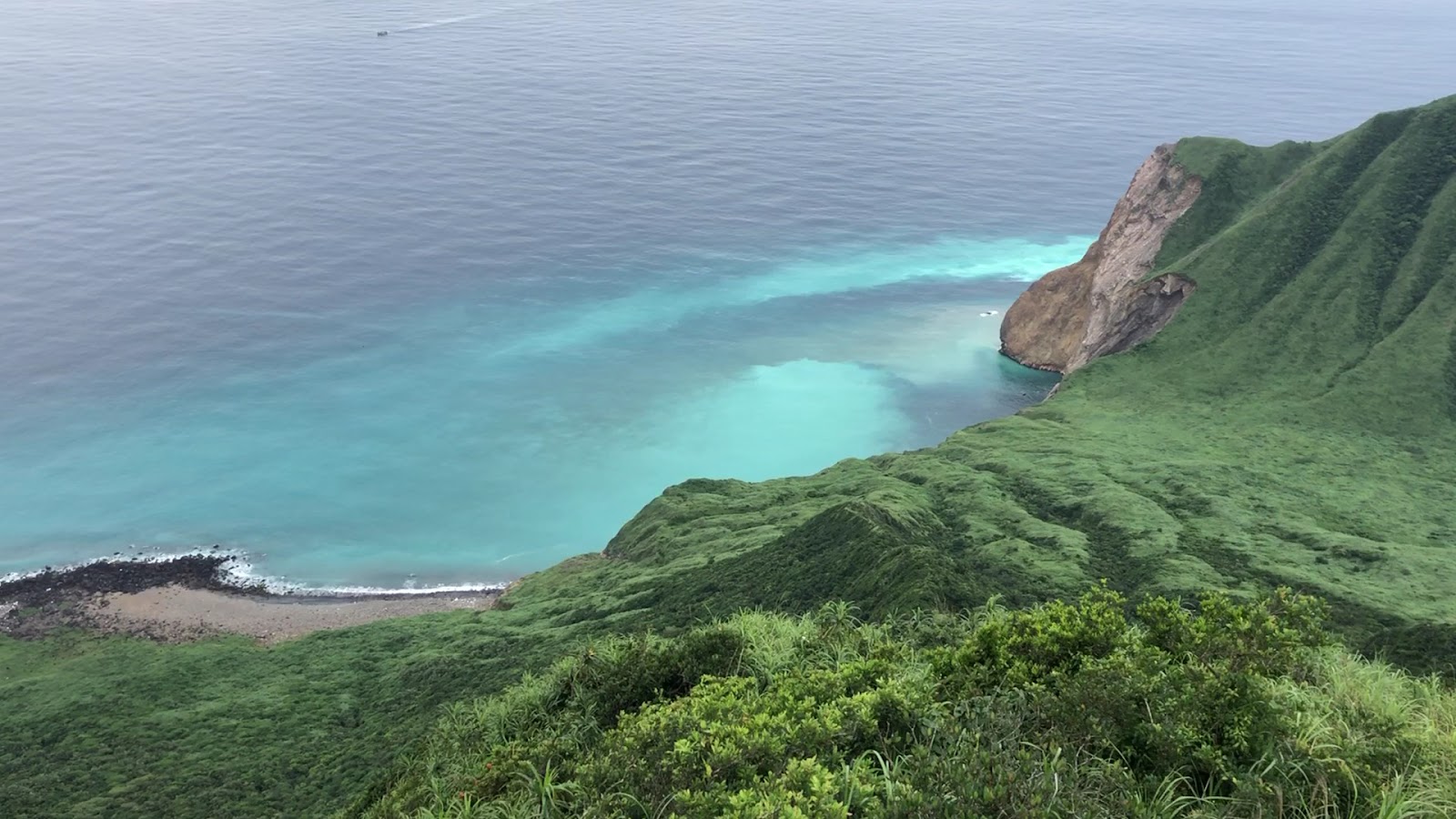 龜山島山頂鳥瞰，前景草地，遠處湛藍海灣