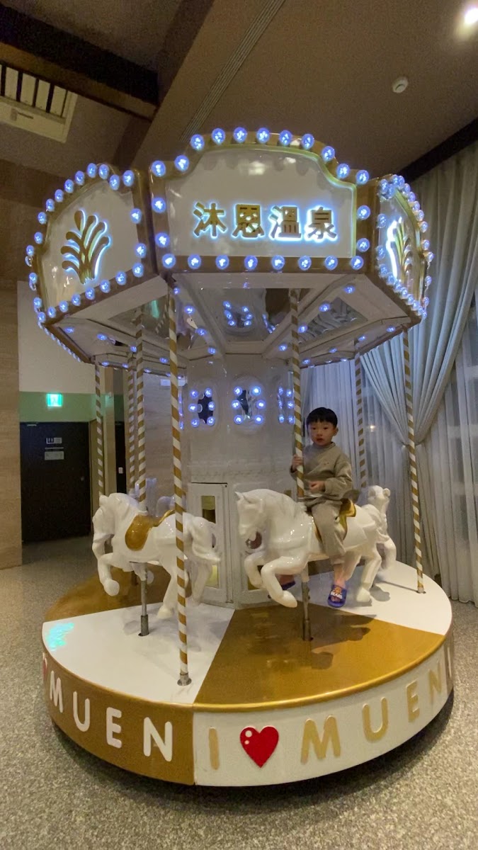 沐恩溫泉旋轉木馬，小孩開心乘騎，沐恩溫泉字樣清晰