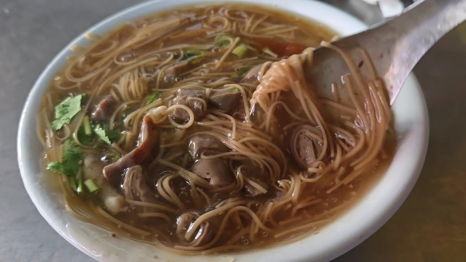 一碗熱騰騰的台灣麵線，內有大腸、香菜和勾芡湯頭