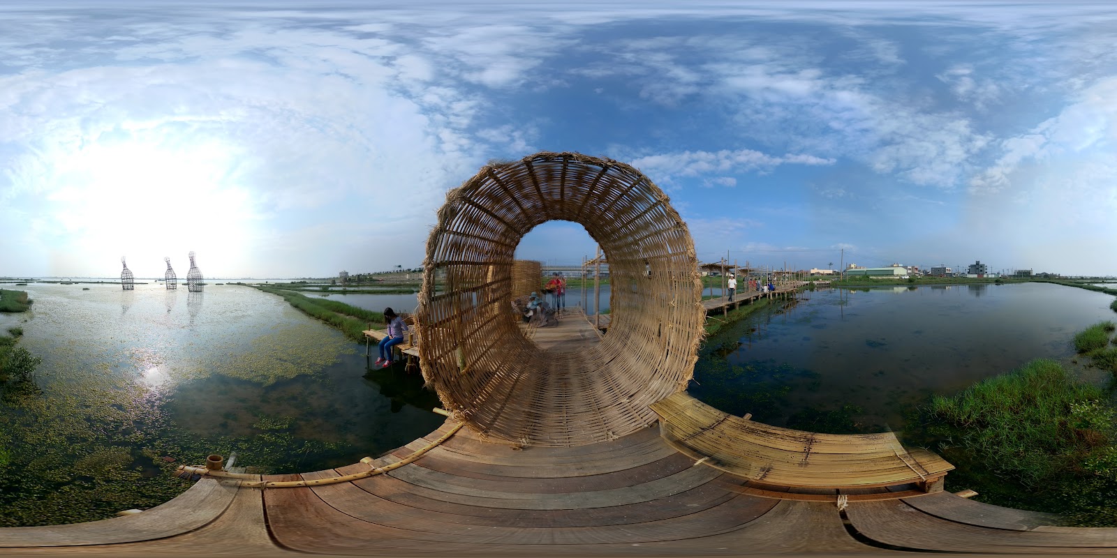 成龍濕地360度全景，竹筌棧道被濕地水面環繞，遠方三個水中裝置藝術