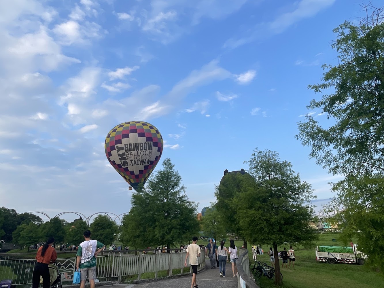 彩色熱氣球升空於藍天下公園草地旁