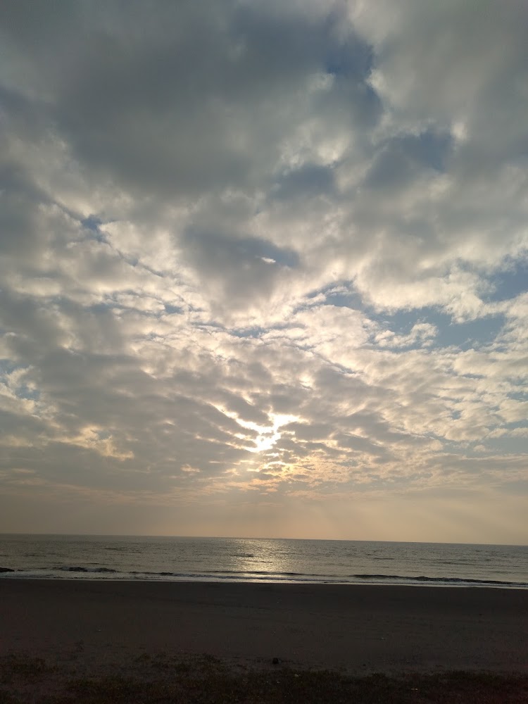 雲層間灑落陽光的海邊日落景色