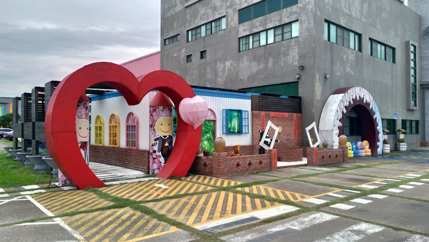 建築物外的主題裝飾景觀，有大型紅色愛心拱門、卡通新郎新娘板、彩色窗框，以及巧克力造型的拱門和笑臉椅子，非常適合拍照留念。
