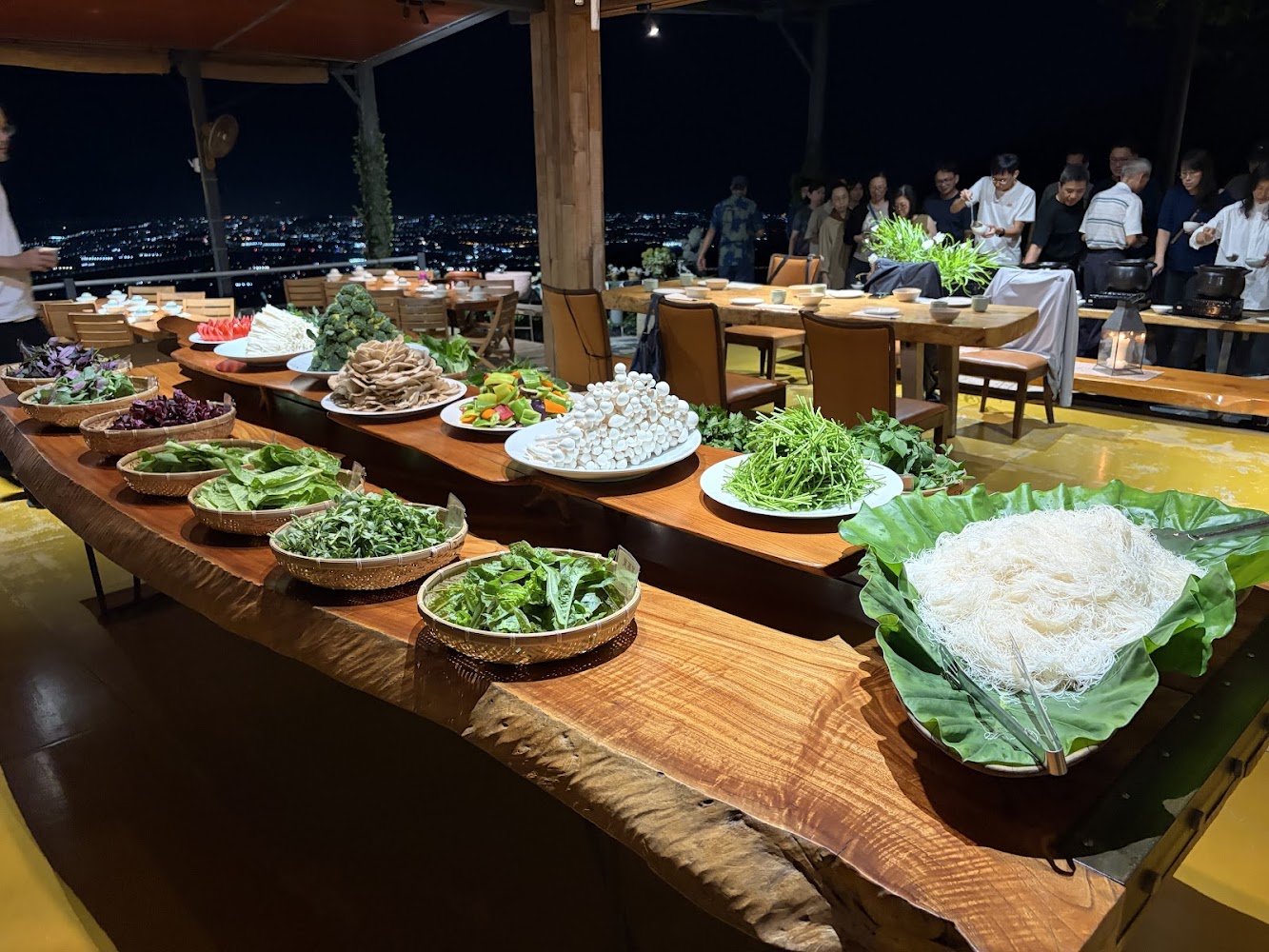 戶外自助餐桌排滿蔬菜菇類粉絲與食材多人排隊取餐