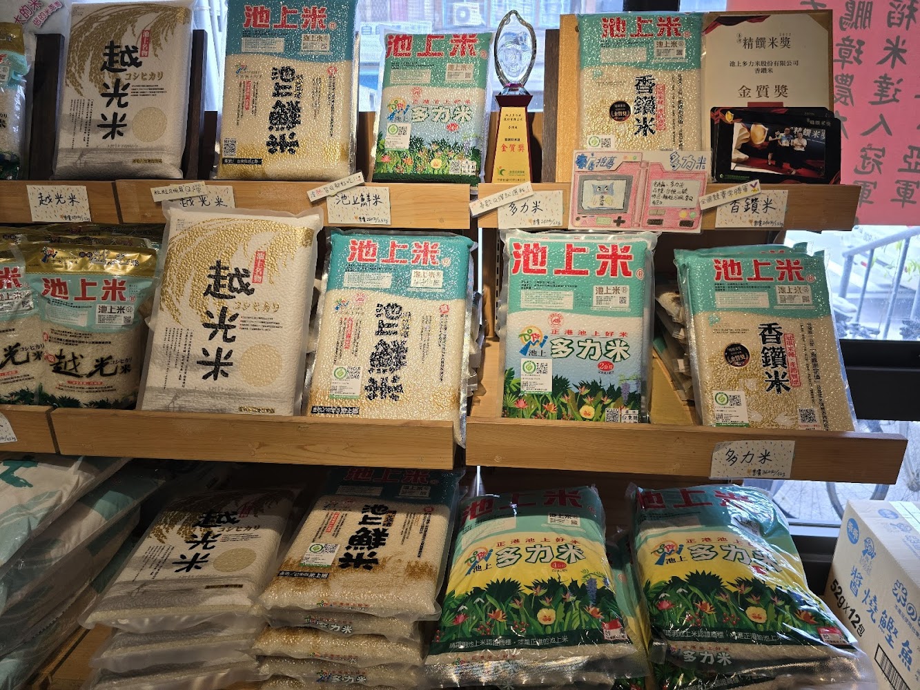 多款不同品牌與品種的米整齊排列在櫃架上，還有獎牌與獎狀