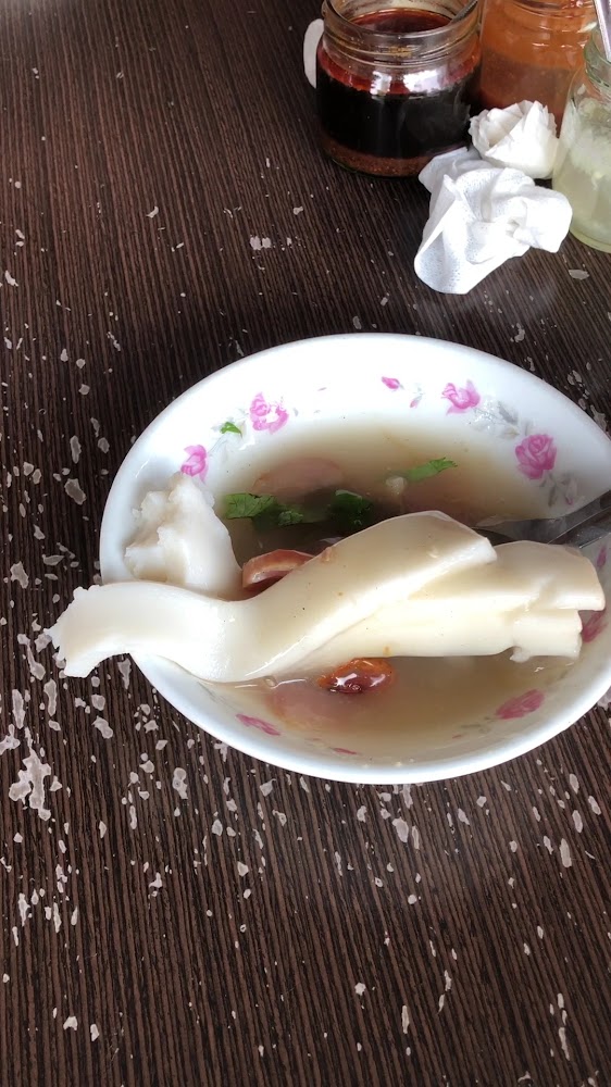 桌上有一碗白色條狀食物的湯品與醬料瓶