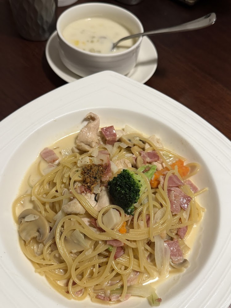 這張圖片主要有一盤奶油培根雞肉義大利麵，搭配花椰菜、蘑菇和蔬菜，旁邊有一碗玉米濃湯，整體看起來非常美味豐盛。