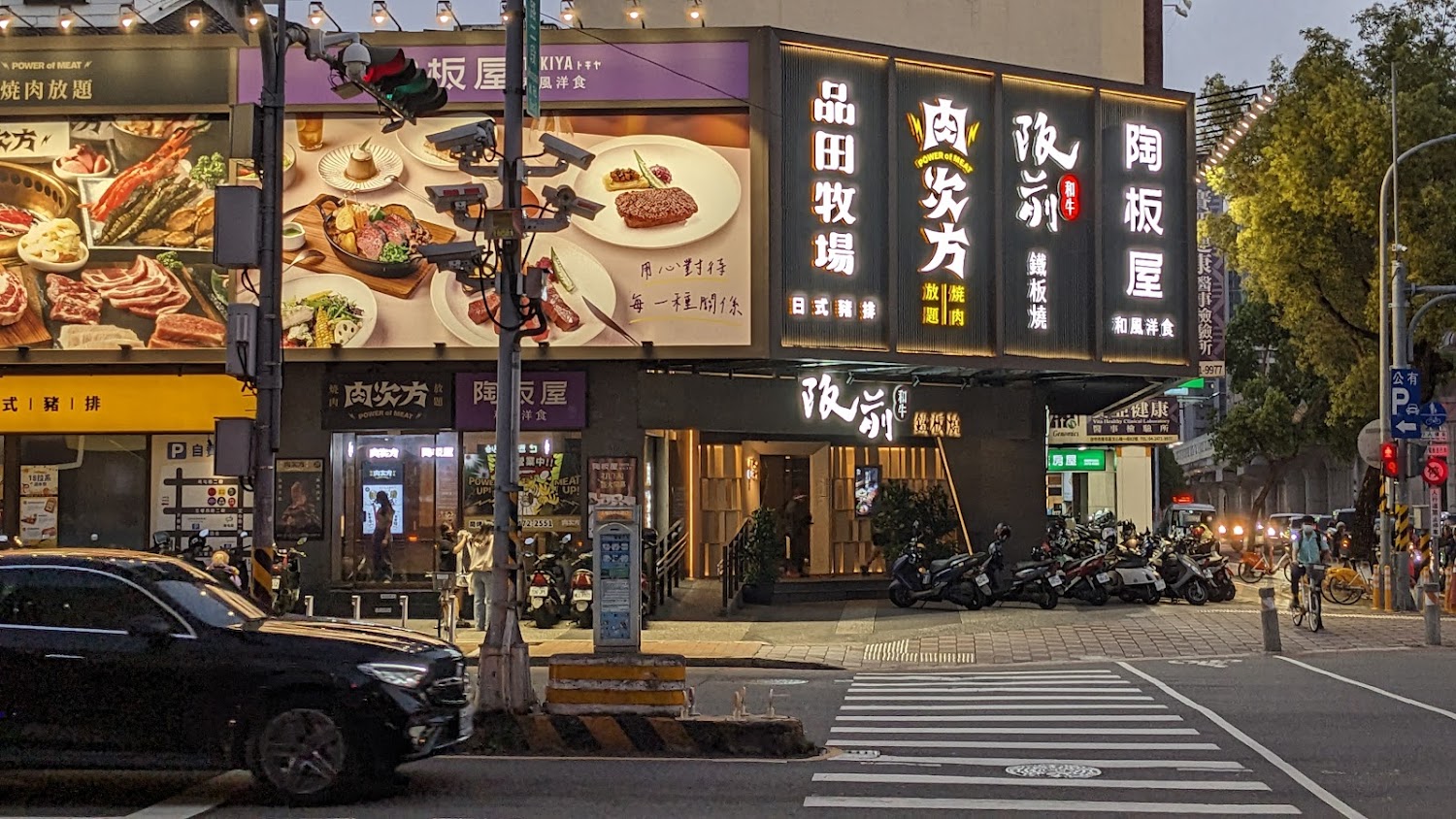 街角的日式燒肉與鐵板燒餐廳店面，外牆有大型美食照片與招牌