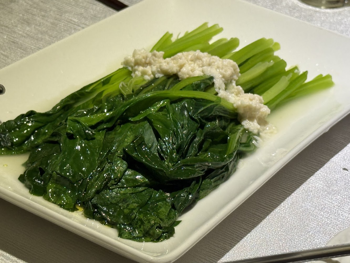 白色長方形餐盤中的燙青菜，上面淋有蒜蓉醬