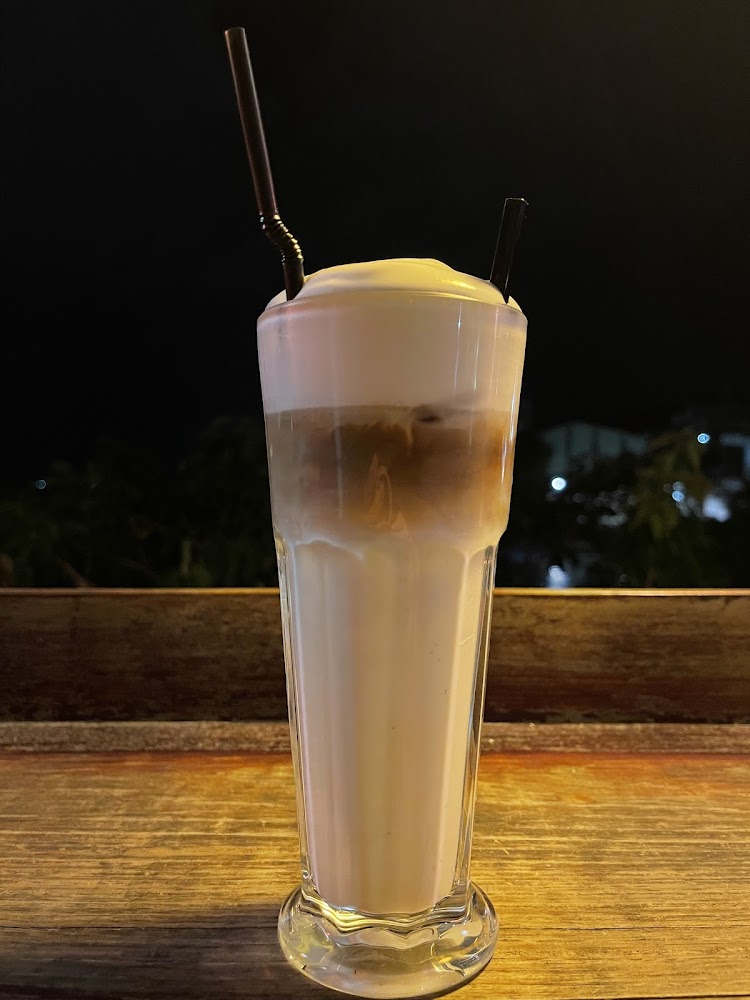 高腳玻璃杯中的冰拿鐵，呈現清楚的奶泡與咖啡漸層
