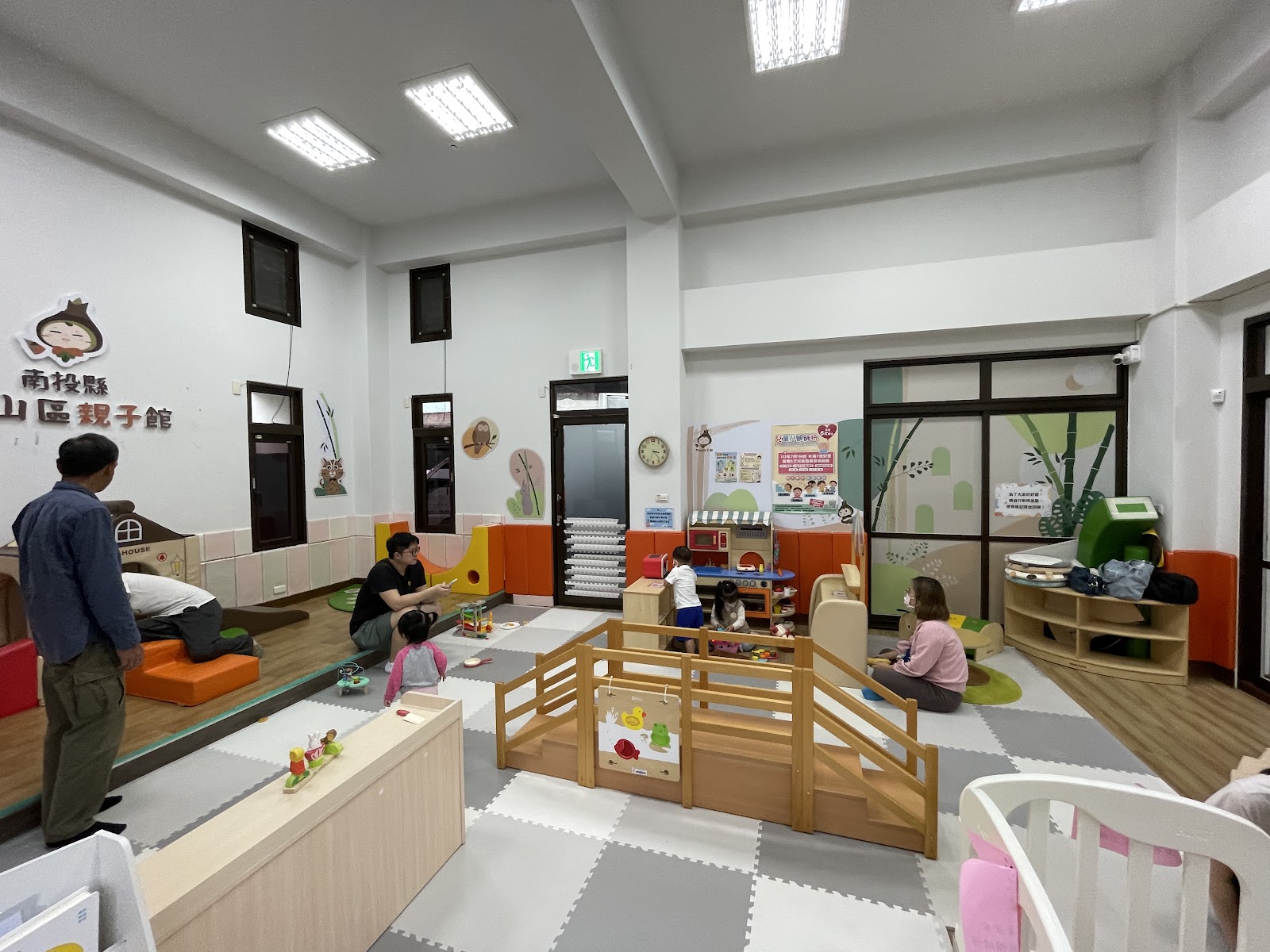 南投縣山區親子館室內兒童遊戲區豐富的木製玩具地墊家長陪伴幼童玩耍