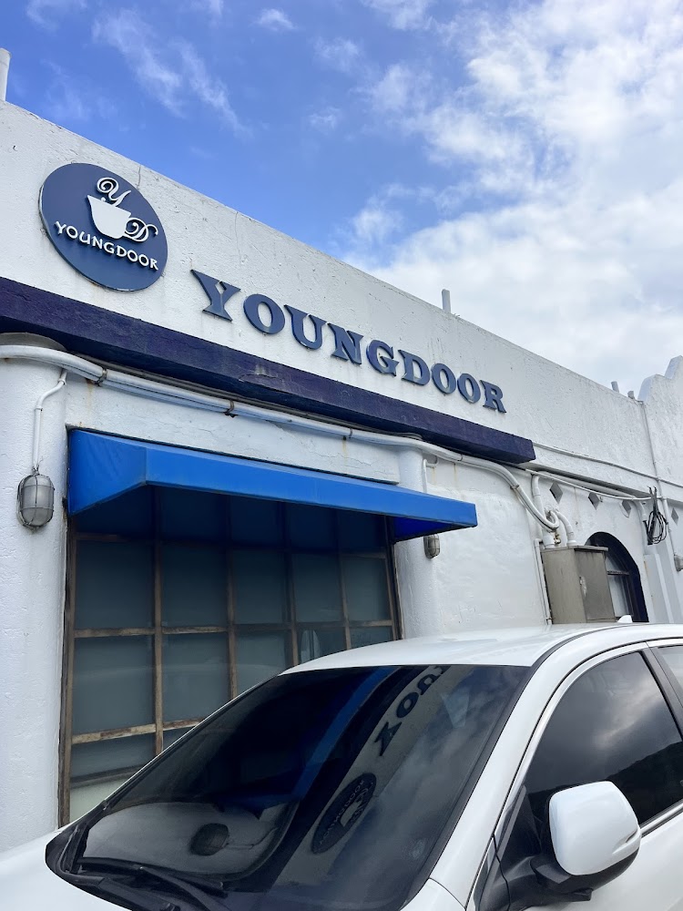 白色店鋪外觀與藍色遮陽棚,招牌上有YOUNGDOOR字樣