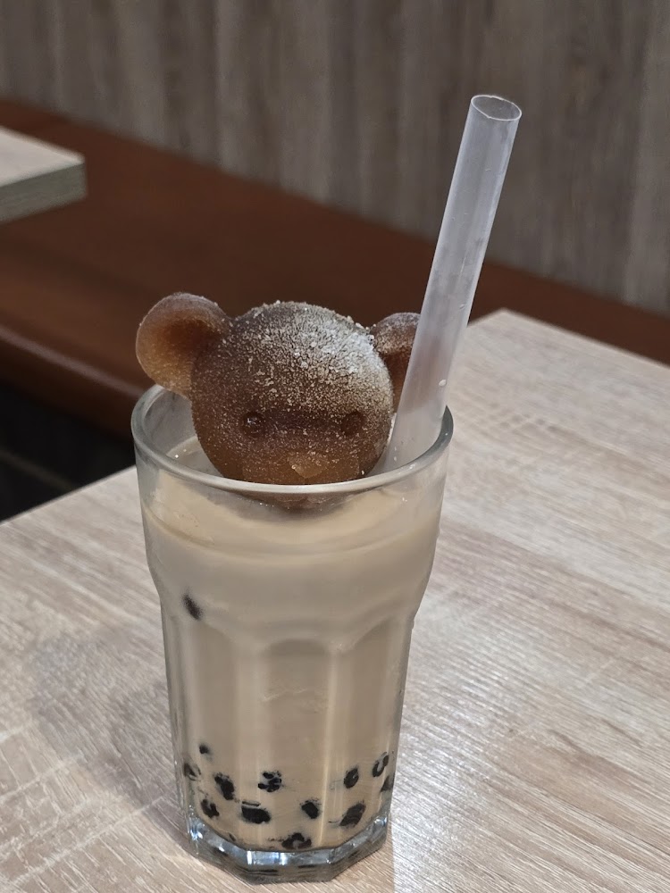 一杯珍珠奶茶，上方有可愛熊造型冰塊。